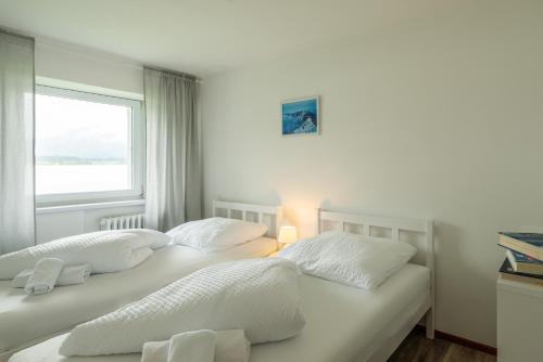 two white beds in a room with a window at Sun Valley Apartments in Maishofen