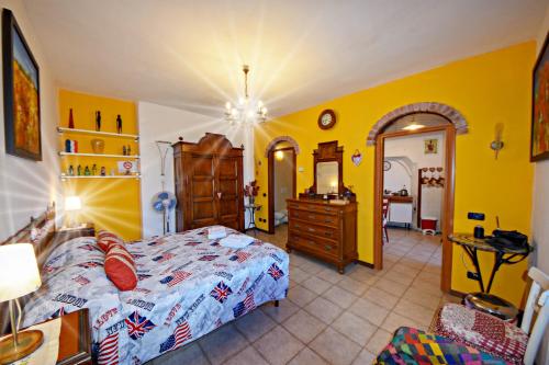 マンデッロ・デル・ラーリオにあるAntica Officinaの黄色の壁のベッドルーム1室、ベッド1台、ドレッサーが備わります。