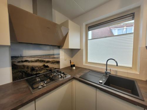 a kitchen with a sink and a stove and a window at Kustverhuur, Park Scheldeveste Zwin 065 in Breskens