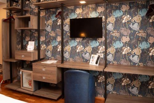 a room with a desk with a tv on a wall at SIRIOHotel in Dormelletto