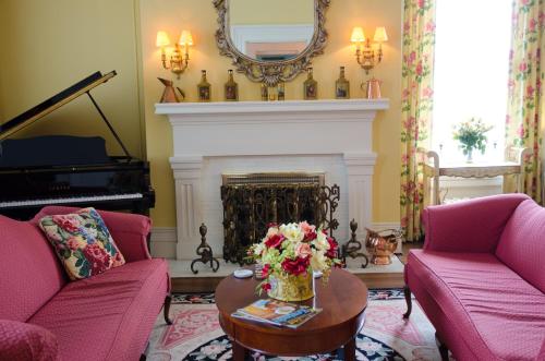 a living room with two pink chairs and a fireplace at Bourbon Manor Bed & Breakfast Inn in Bardstown