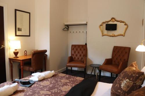 a hotel room with a bed and two chairs at Milling Hotel Saxildhus in Kolding