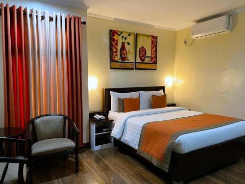 um quarto de hotel com uma cama e uma cadeira em Subic Residencias em Olongapo