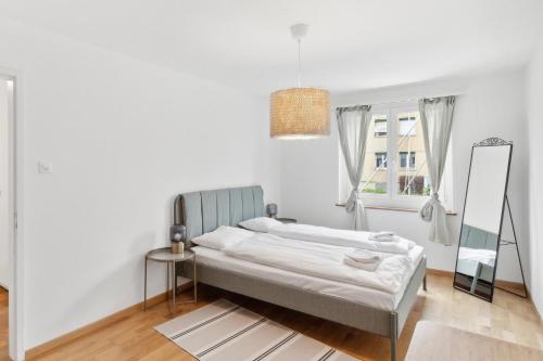 a white bedroom with a bed and a mirror at Dübendorfstrasse 171 in Zurich