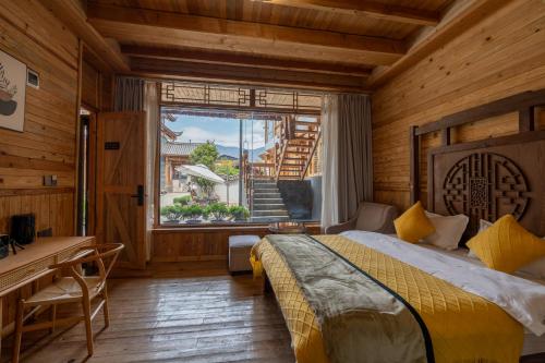 um quarto com uma cama, uma secretária e uma janela em Lijiang Shitian B&B em Lijiang