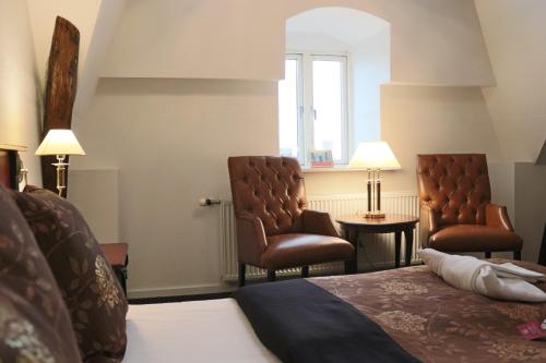 a hotel room with a bed and two chairs at Milling Hotel Saxildhus in Kolding
