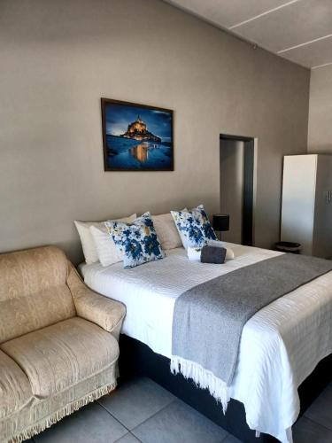 a bedroom with a large bed and a couch at Oppi Draai Guesthouse in Oudtshoorn