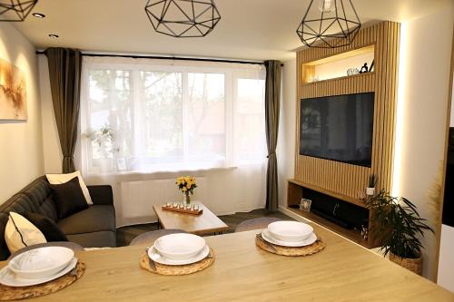 ein Wohnzimmer mit einem Tisch und einem TV in der Unterkunft Gape Apartment in Limbaži