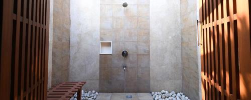 a shower stall in a bathroom with rocks in it at The Golkonda Resort and Spa in Hyderabad