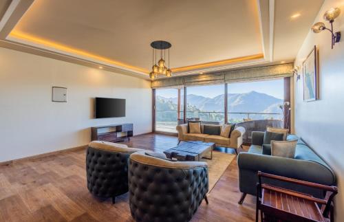 a living room with a couch and chairs and a tv at The Manor Luxury Apartments, Shimla in Mashobra