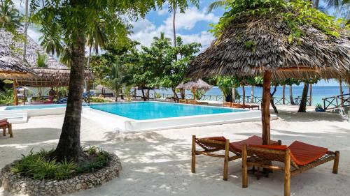 - une piscine avec des chaises longues et un parasol dans l'établissement MANOLO Beach Resort, à Uroa