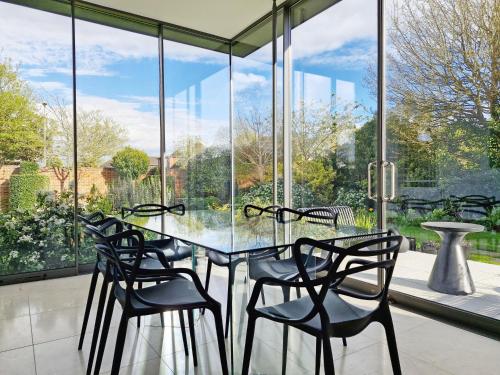 a glass table and chairs in a room with windows at Blythe House - Emsworth in Emsworth