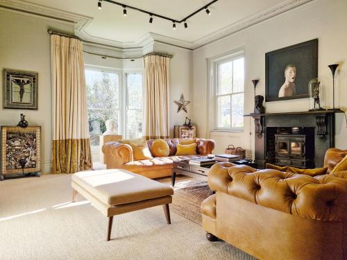 a living room with leather furniture and a fireplace at Blythe House - Emsworth in Emsworth