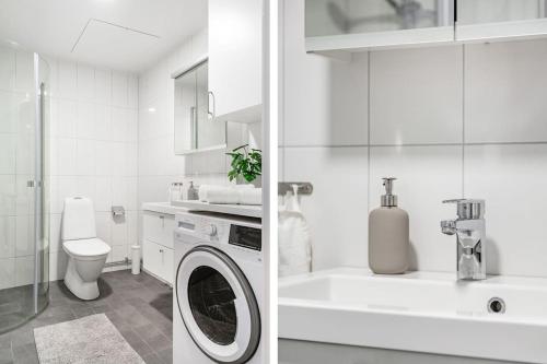 baño blanco con lavadora y lavamanos en Modern Stylish Apartment With Balcony In Stockholm, en Järfälla