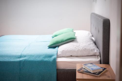a bed with green pillows and a table with a book at Sun Valley Apartments in Maishofen