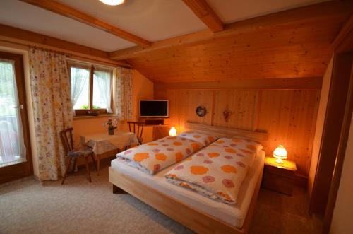 1 dormitorio con cama, mesa y TV en Gästehaus Friedl, en Kirchberg in Tirol