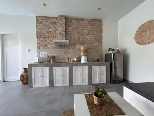 a kitchen with white cabinets and a brick wall at Pineale Villas, Resort and Spa in Panglao