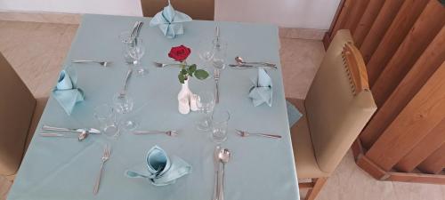 een witte tafel met wijnglazen en een roos erop bij Z Addis Hotel in Addis Ababa