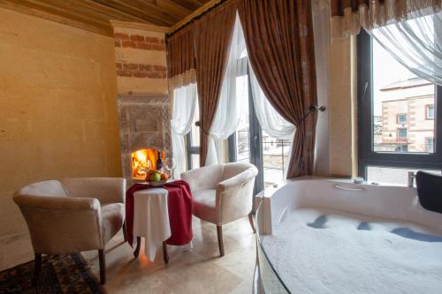 uma casa de banho com uma banheira, 2 cadeiras e uma mesa em Milagro of Cappadocia em Üçhisar