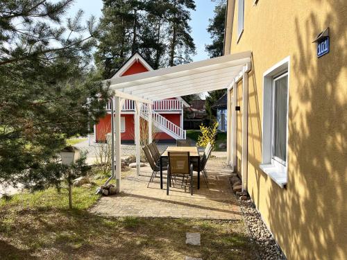 un patio con mesa y sillas junto a una casa en "Strandhaus" Unter den Kiefern 101, en Marienfelde