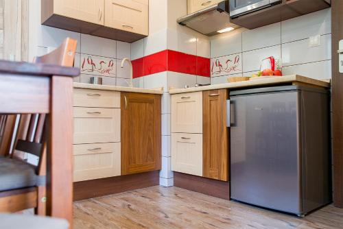 eine Küche mit weißen Schränken und einem schwarzen Kühlschrank in der Unterkunft Apartament Pod Bukami Wisła Bukowa in Wisła