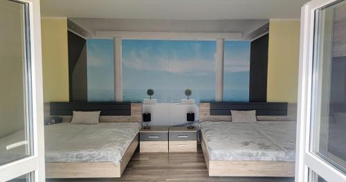 two beds in a room with a view of the ocean at bellavitavilla2020 in Siófok