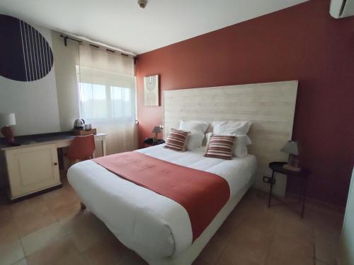 a bedroom with a large bed with a red wall at Hôtel Restaurant L'Art des Mets by Côté Jardin in Conilhac-Corbières