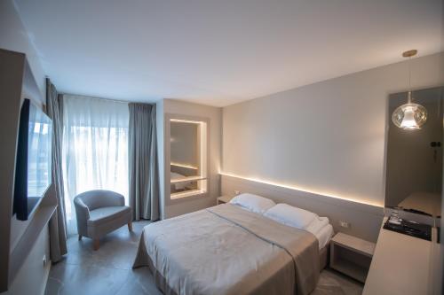 Hotel Atena*** في ساتورن: غرفه فندقيه بسرير وكرسي