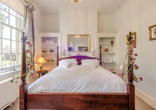 a bedroom with a large bed with a purple headboard at The Lake House - Crimplesham Hall in Stradsett