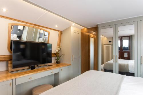 a bedroom with a flat screen tv and a bed at Luxus Hausboot am Pichelssee - Madame President in Berlin