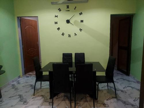 ein Esszimmer mit einem Tisch und einer Uhr an der Wand in der Unterkunft Cool meuble 2 in Ouagadougou