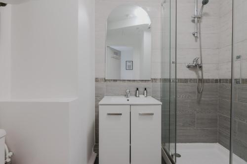 een witte badkamer met een wastafel en een douche bij CMG Batignolles - Lechapelais II in Parijs