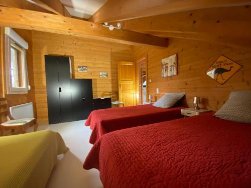 a bedroom with two beds in a wooden cabin at Gîte Autre Ruche in Baudement