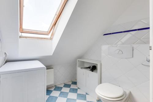 La salle de bains blanche est pourvue de toilettes et d'une fenêtre. dans l'établissement Cozy & Quiet Center Attic with Castle view - vtuB, à Prague