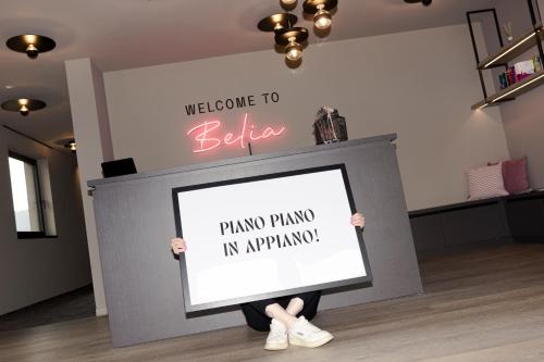 a person holding a sign in front of a wall at Belia Lofts - ADULTS ONLY - Apartments in Appiano sulla Strada del Vino