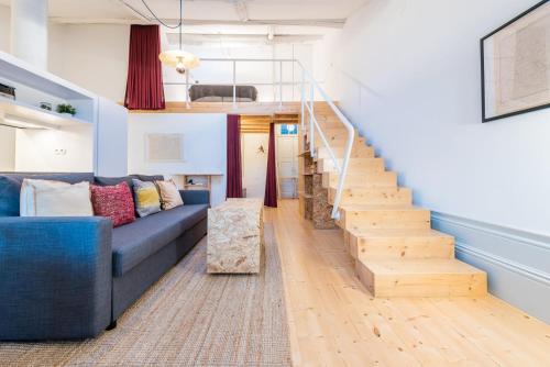 a living room with a blue couch and stairs at GuestReady - Mezzanine at the Bridge in Porto