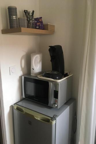 a microwave sitting on top of a refrigerator at Les chambres d'Ursule in Tartas