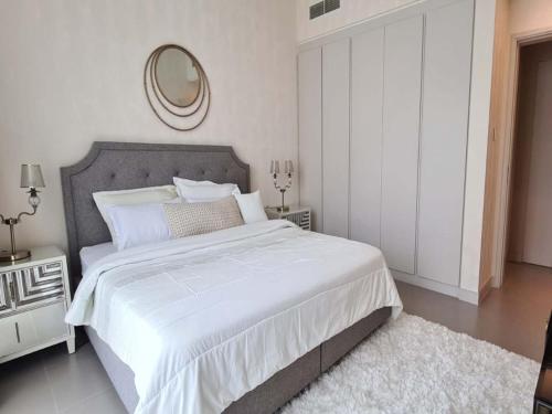 1 dormitorio blanco con 1 cama grande y espejo en Marassi shores - 310, en Durrat Al Bahrain