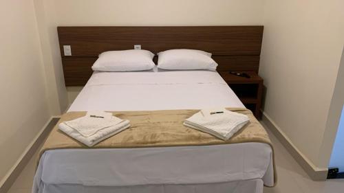 ein Schlafzimmer mit einem Bett mit zwei Handtüchern darauf in der Unterkunft Lazzaru's Hotel in Alexânia