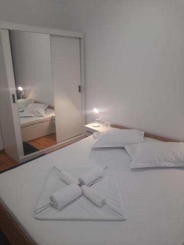 a white bed with two bowties on it in front of a mirror at Apartament Nicol in Drobeta-Turnu Severin