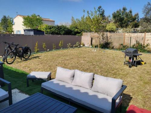 - un canapé bleu dans une cour avec un grill et une bbqarmaarma dans l'établissement ! NEW ! Maison neuve classée 3* Saint palais, à Saint-Palais-sur-Mer