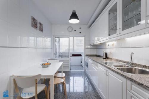 a white kitchen with a sink and a table at Gaia Beach & Pool Residence - Porto South Seashore in Vila Nova de Gaia