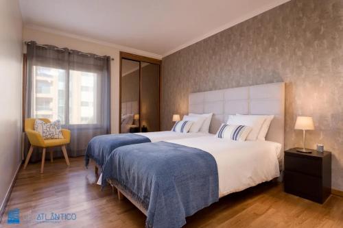 una habitación de hotel con 2 camas y una silla en Gaia Beach & Pool Residence - Porto South Seashore, en Vila Nova de Gaia