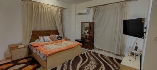 sypialnia z łóżkiem i telewizorem z płaskim ekranem w obiekcie فيلا العائلة w mieście ‘Ezbet Sharikât Wardan