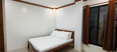 a small bed in a room with a window at Casa Victoria Pension House-Makra in Somosomo
