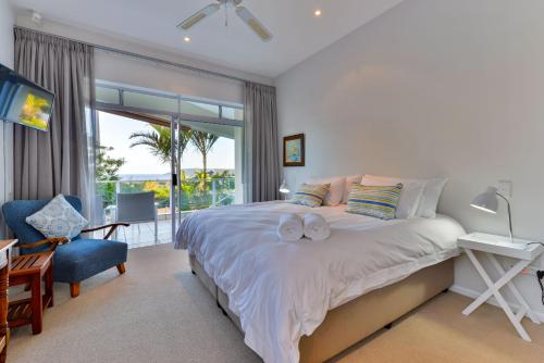 a bedroom with a bed and a chair and a window at Plettenberg View in Plettenberg Bay