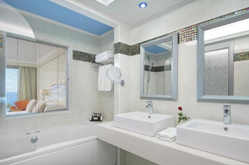 a white bathroom with two sinks and a mirror at Atrium Platinum Resort & Spa in Ixia