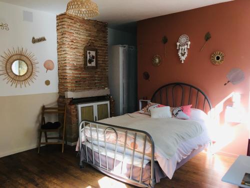 - une chambre avec un lit et un mur en briques dans l'établissement Les chambres d'Ursule, à Tartas