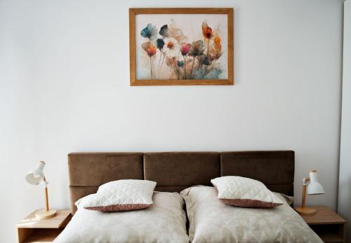 a bed with two pillows and a picture on the wall at Magic Apartments - Bulwary 3 in Oświęcim
