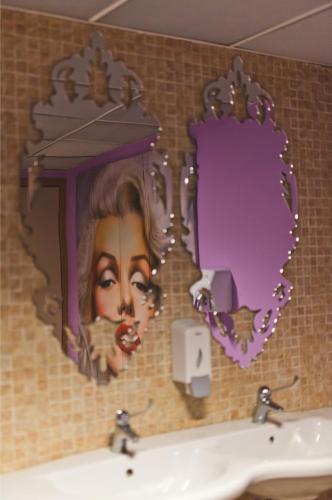 a bathroom with a painting of a woman in a mirror at Albergo Athenaeum in Palermo